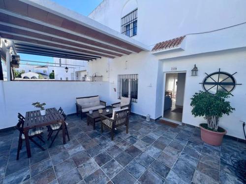 a patio with chairs and tables on a white wall at Chalet en Real de la Barrosa in Chiclana de la Frontera