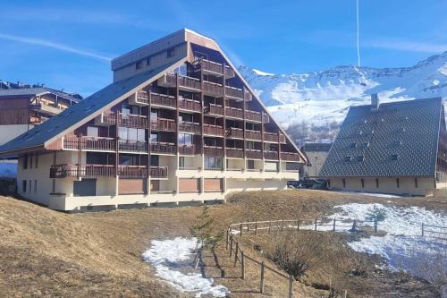 un bâtiment sur une colline avec des montagnes en arrière-plan dans l'établissement Appartement 4 personnes au pied des pistes, à Saint-François-Longchamp