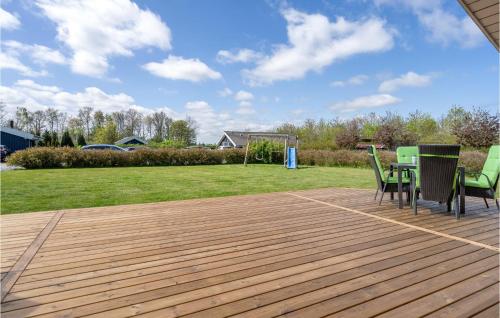 a wooden deck with chairs and a table on it at Holiday Home Strandparken Xi in Otterup