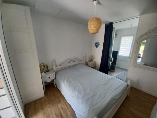 une chambre avec un lit blanc et un miroir dans l'établissement La Piastre Location à la semaine, à Saint-Hilaire-de-Riez
