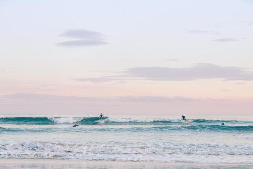 a group of surfers riding the waves in the ocean at Deluxe family home near beach with views sleeps 10-12 in Ocean Grove