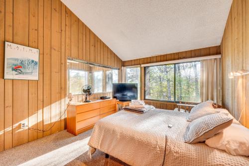 een slaapkamer met houten wanden, een bed en een televisie bij All-Season Conway Condo with Private Hot Tub! in North Conway