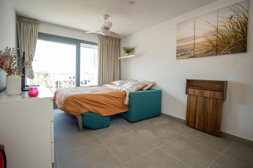 1 dormitorio con 1 cama con silla azul y ventana en Zeebries Studio, en Ostende