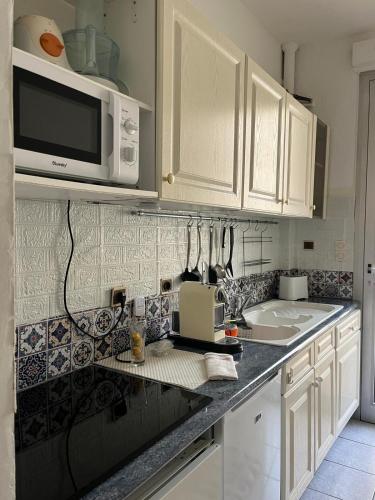 une cuisine avec des armoires blanches et un micro-ondes dans l'établissement Appartement 20 mts plage, pl Méditerranée, vue mer parking, à Canet