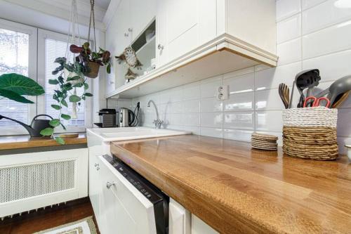 a kitchen with white cabinets and a wooden counter top at cozy urban hideaway - with a sauna! in Jáma Jindřich