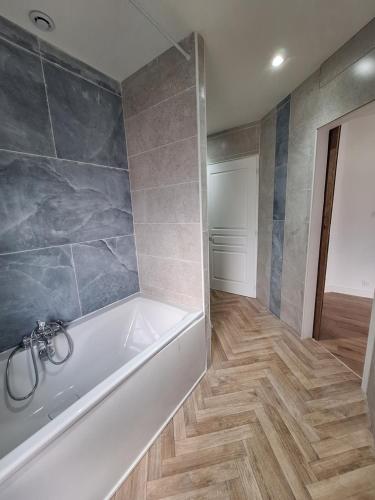 a bathroom with a white tub and a wooden floor at Le spot Landais - Côté piscine in Soustons