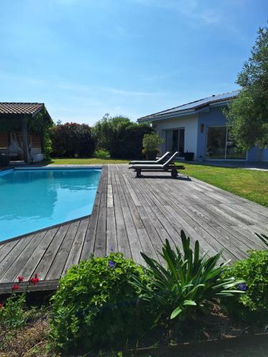 a wooden deck next to a swimming pool at Le spot Landais - Côté piscine in Soustons
