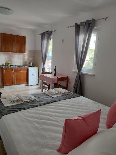 a bedroom with a large bed and a kitchen at Apartments Glibić in Zaostrog