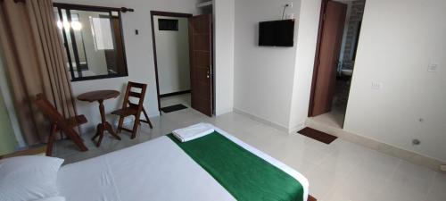 Amaca Suites في سانتا كروز دي لا سيرا: غرفة نوم مع سرير مع بطانية خضراء عليه