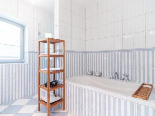 - une salle de bains blanche pourvue d'une baignoire et d'une étagère dans l'établissement Dünenhof DÜNENHOF Whg. D-11, à Wustrow