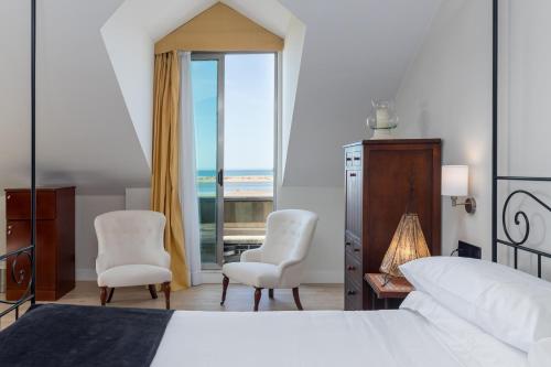 a bedroom with a bed and two chairs and a window at Hotel Milagros Golf in Mogro