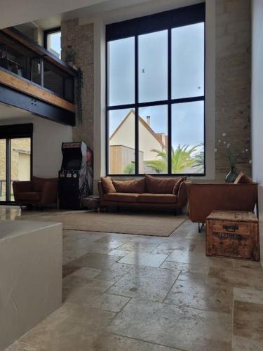 un grand salon avec des canapés et une grande fenêtre dans l'établissement La Bergerie - Good Vibes Home, à Basly