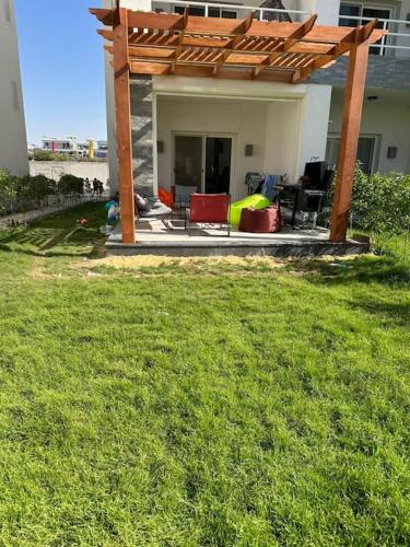 a patio with a pergola and chairs in a yard at Amwaj private chalet with grill in Sīdī ‘Abd ar Raḩmān
