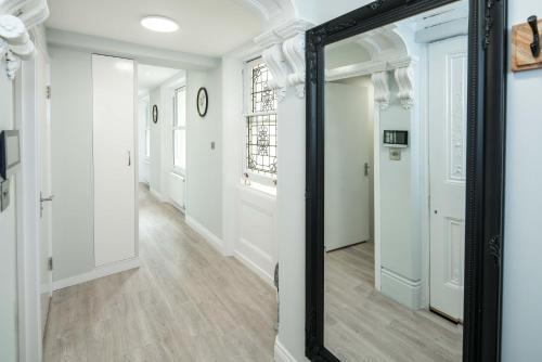 espejo en un pasillo con paredes blancas y suelo de madera en Tranquil Trio Bedrooms, en Londres
