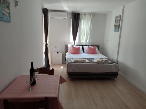 a bedroom with a bed with pink pillows and a table at Apartments Glibić in Zaostrog