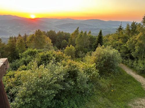 a sunset over the mountains and trees with the sun setting at Willa Wioletta in Tylmanowa