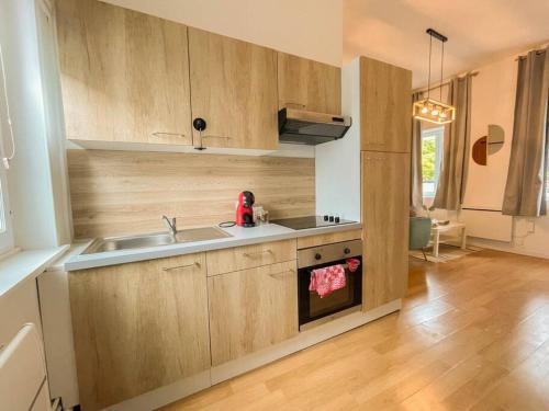une cuisine avec des armoires en bois et un évier dans l'établissement Le moineau -Poterne -Parking gratuit -Calme-Centre, à Valenciennes