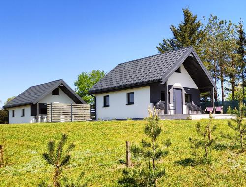 une maison blanche avec un toit noir dans un champ dans l'établissement Na Zaciszu, à Cierzpięty