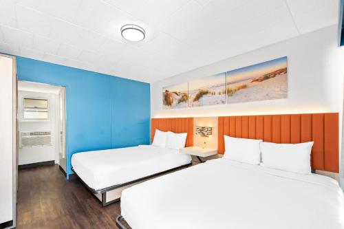 twee bedden in een kamer met blauwe muren bij Tropicana Motel in Wildwood