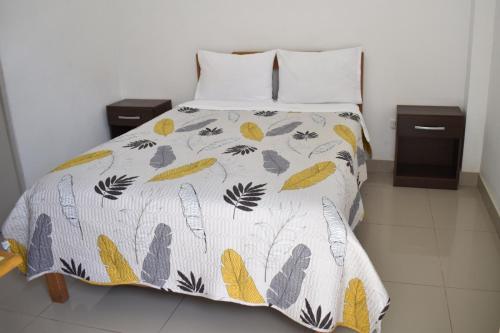 Una cama con un edredón con hojas. en Hospedaje El Buen Samaritano, en Paracas