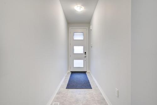 an empty corridor with a white door and a blue rug at Niagara Falls Luxury Living - 8 GUEST HOUSE in Niagara Falls