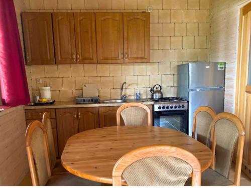 a kitchen with a wooden table and a refrigerator at Domek Pod Lasem in Pozezdrze