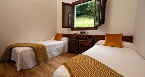 zwei Betten in einem Zimmer mit Fenster in der Unterkunft La casina de Peñaullan in Pravia