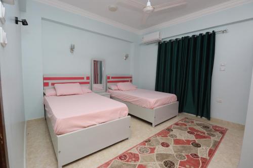 two beds in a bedroom with green curtains and a rug at Ramsses Palace in Luxor