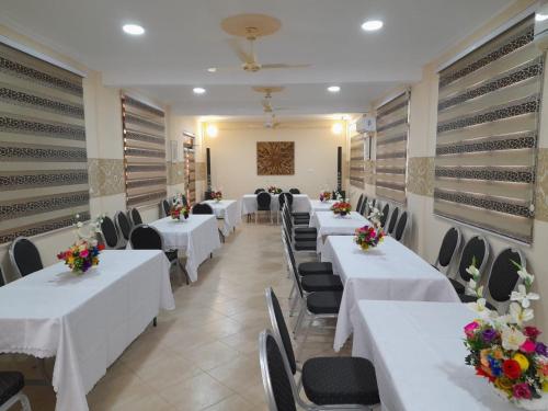 un restaurante con mesas blancas y sillas con flores. en Dominion Embassy Lodge en Takoradi