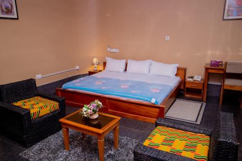 a bedroom with a bed and two chairs and a table at Dominion Embassy Lodge in Sekondi-Takoradi