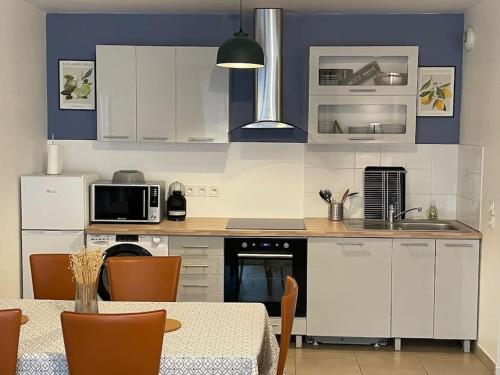 une cuisine avec des armoires blanches et une table avec des chaises dans l'établissement Charmant appart près du métro et aux portes de Paris, à Saint-Ouen