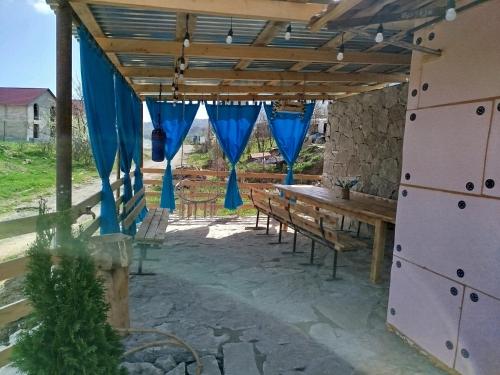 een patio met een houten tafel en blauwe gordijnen bij Elegant House in Dilidzjan