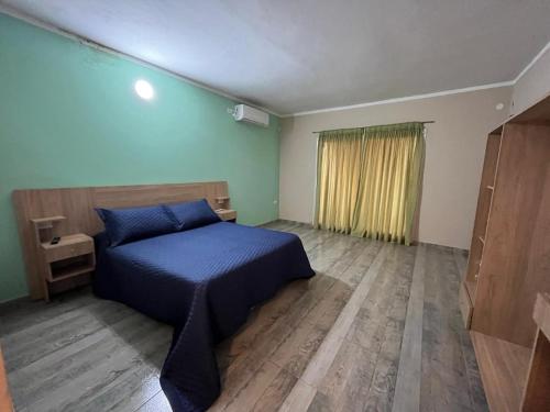 um quarto com uma cama azul e piso em madeira em Complejo Aloe Vera D em Villa Dolores