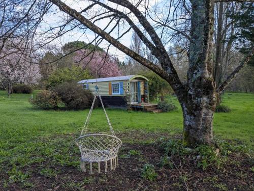 a swing hanging from a tree in front of a caravan at Graines de nature - Ecolodges Insolites in Saint-Eutrope-de-Born