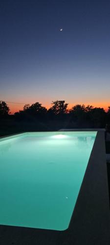 uma piscina com iluminação azul em frente a um pôr-do-sol em Monte do Rochinha em Monte da Cardosa