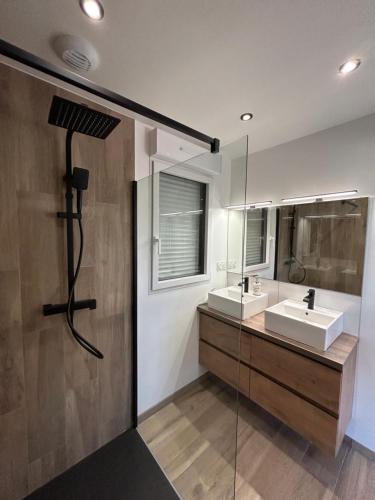 a bathroom with two sinks and a glass wall at Gite avec Spa Le Rubis proche des plages du Débarquement Manche Normandie in Joganville