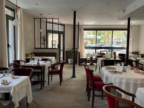 a restaurant with white tables and chairs and windows at HÔTEL PARIS VÉSINET- Logis Hôtel Restaurant in Le Vésinet