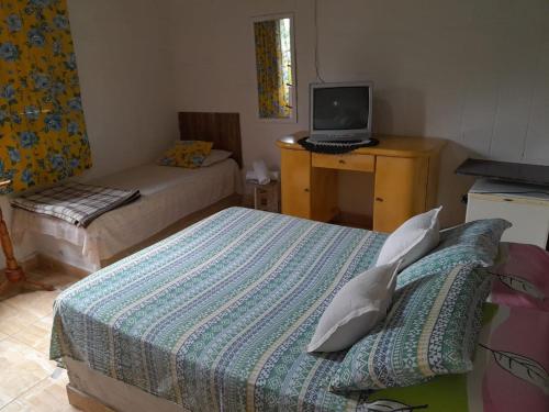 a bedroom with two beds and a laptop on a desk at Pousada Bora Bora in Guarapari
