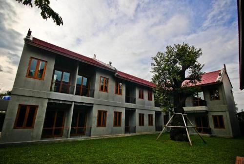 a building with a tree in front of it at Chu Hotel in Chiang Mai