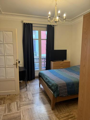 une chambre avec un lit, une télévision et une fenêtre dans l'établissement 3 pièces 64 m2 dans Paris 16, 2 minutes du métro Michel Ange Auteuil, 6 personnes, à Paris