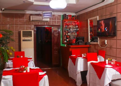 un restaurante con mesas rojas y sillas rojas en una habitación en Definite Destiny Hotel by YOTRAD, en Lagos