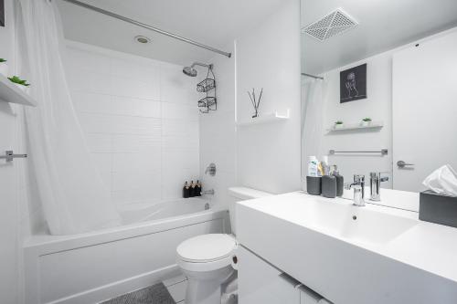 a white bathroom with a tub and a toilet and a sink at Stunning Luxurious LakeView Condo by CN Tower in Toronto