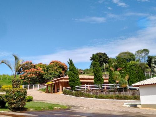ein Haus mit einem Zaun und Bäumen im Hintergrund in der Unterkunft Pousada Vale do Café in Bueno Brandão