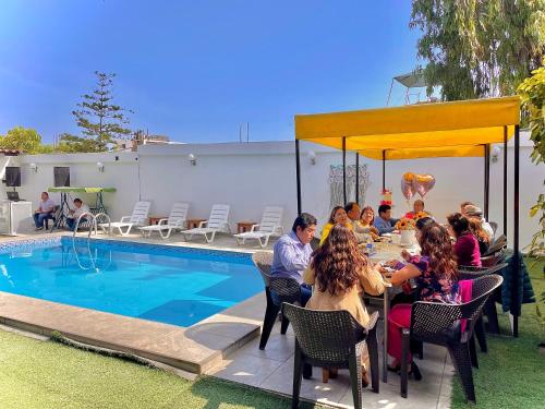 a group of people sitting around a table by a pool at HUANCHACO GARDENS in Huanchaco