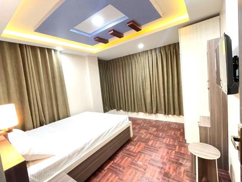 Habitación de hotel con cama y TV en Applewood Inn en Katmandú