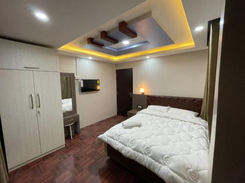 a bedroom with a white bed and a tv at Applewood Inn in Kathmandu