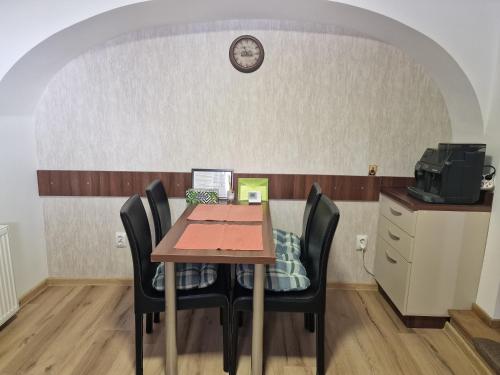 tavolo con sedie e orologio su muro di Apartament Lucretia - Centrul Sibiului a Sibiu