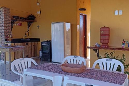 cocina con mesa, sillas blancas y nevera en Chácara Beira Rio - NX -MT, en Chavantina