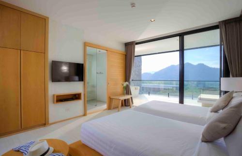 a bedroom with a large bed and a large window at Botanica Khao Yai by Scenical in Mu Si