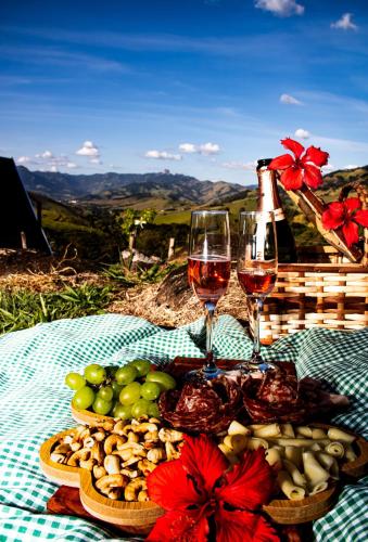 a picnic table with two glasses of wine and food at Chalé Magia do Serrano in São Bento do Sapucaí